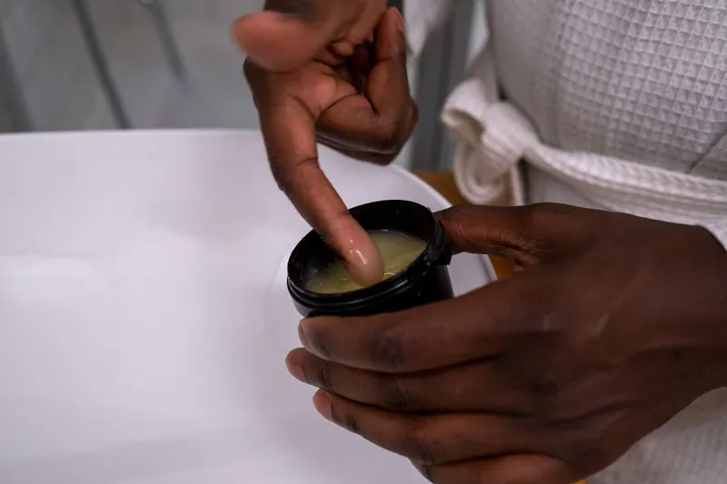 Detail of hands applying moisturizing cream from a container. Ideal for skincare and beauty concepts