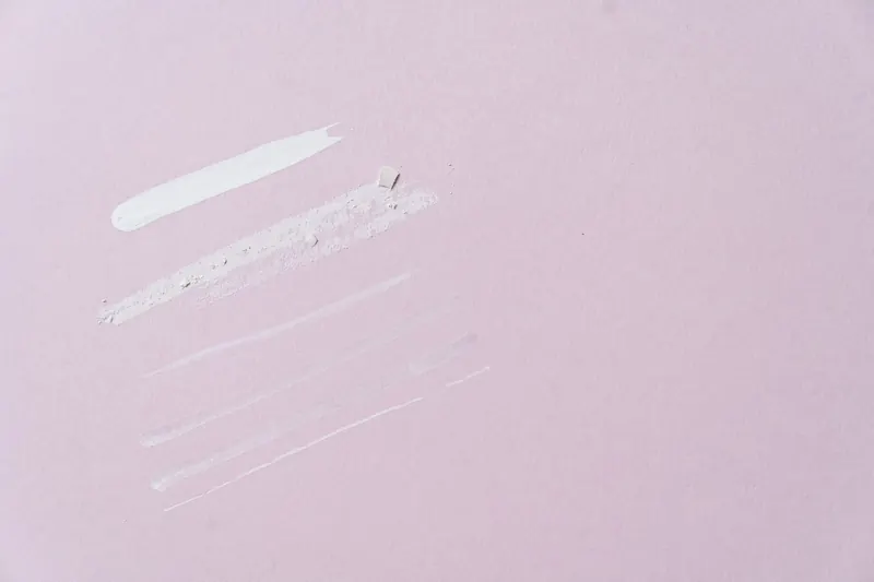 Flat lay of skincare product swatches on a pastel pink background, ideal for beauty and cosmetics themes