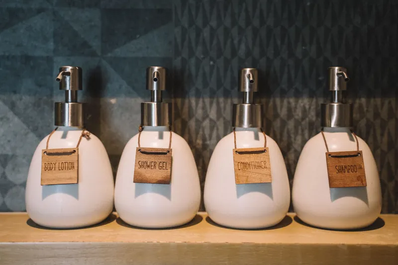 Elegant pump bottles holding bath essentials like lotion, gel, and more on a wooden shelf