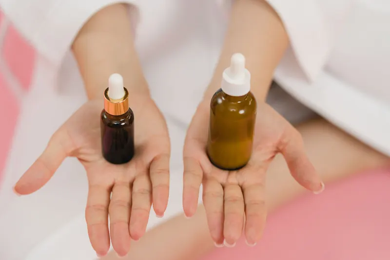Close-up of hands holding two cosmetic dropper bottles for skincare routine