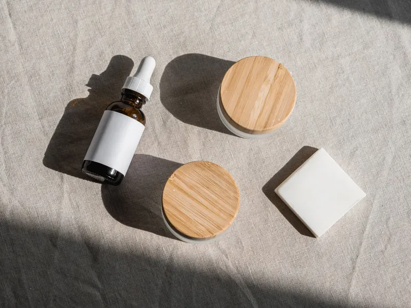 Flat lay of natural skincare products with wooden lids on a linen fabric background, perfect for eco-friendly branding