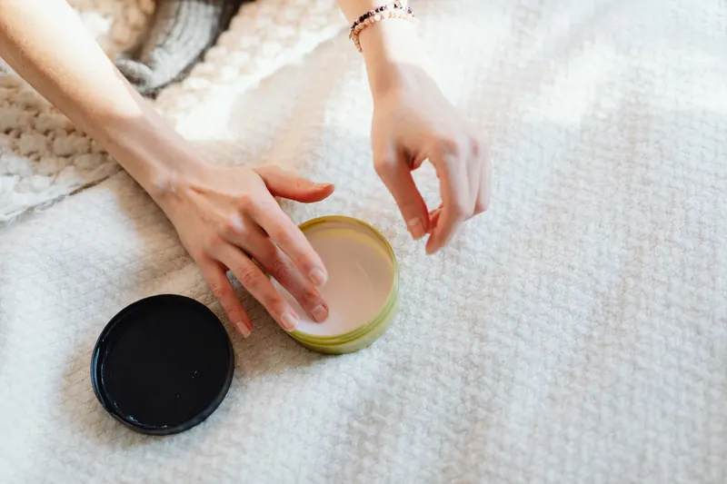 Close-up of hands applying cream on a soft, textured surface, emphasizing relaxation and skincare routine