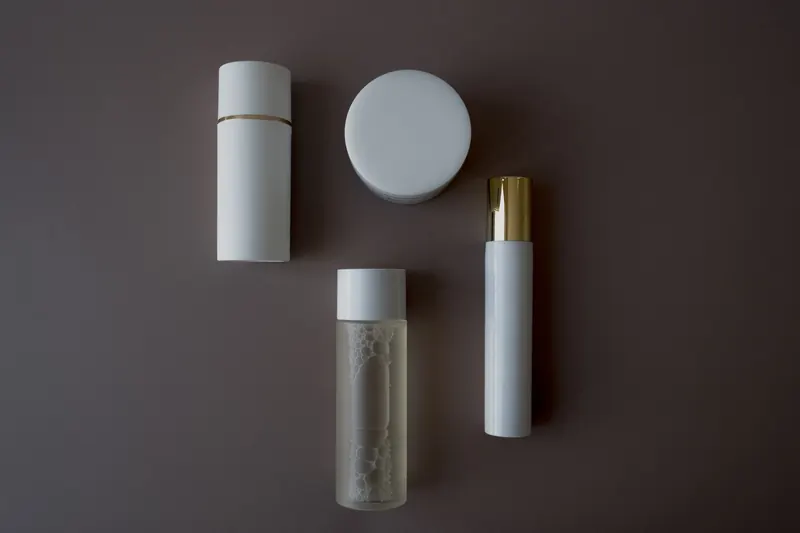 Top view of various skincare bottles and flasks on a sleek gray background