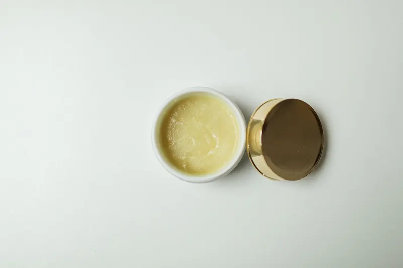 Top view of an open skincare cream jar with a gold lid on a white background for beauty and skincare concepts