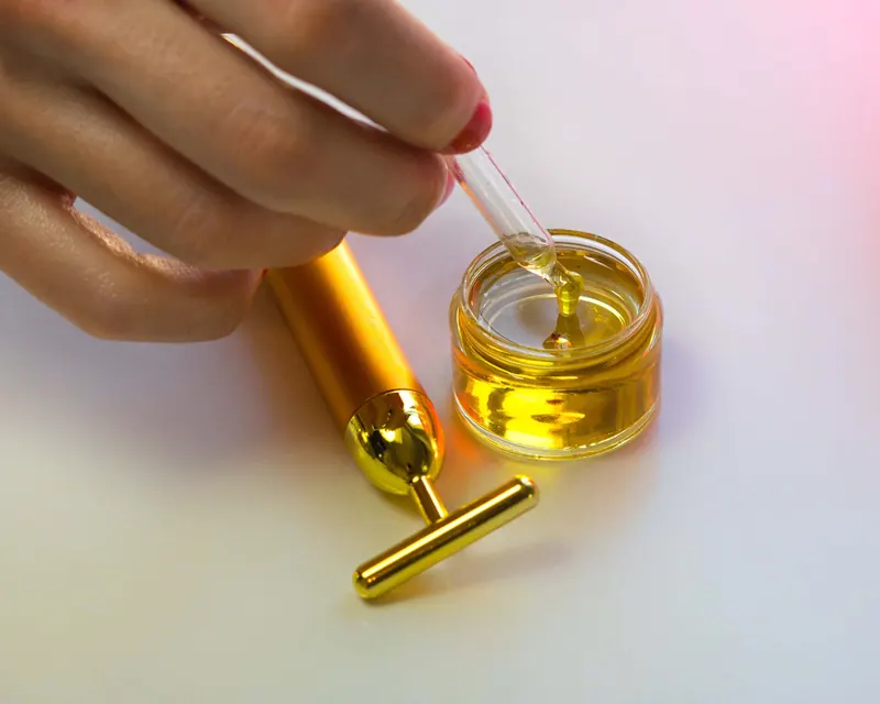 Close-up of a hand handling a serum dropper with massage tool showcasing luxury skincare routines