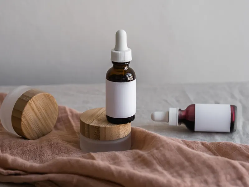 Elegant skincare bottles and jars with bamboo lids on a bright background