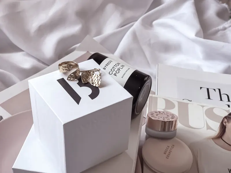 Stylish arrangement of luxury beauty items and jewelry on a white sheet setting