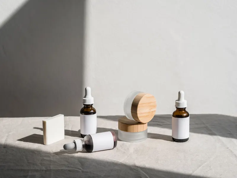 Flat lay of skincare products in jars and dropper bottles under soft natural light